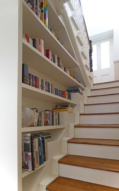 there are many books on the shelves next to the stairs