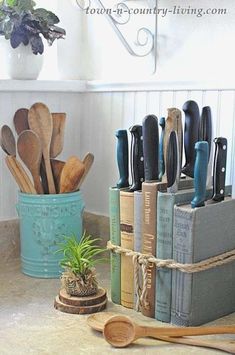 kitchen utensils and wooden spoons are sitting on the counter next to books