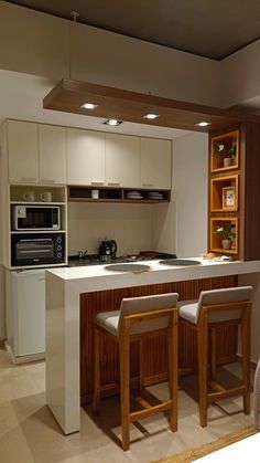 a kitchen with an island and bar stools next to the stove top oven in it