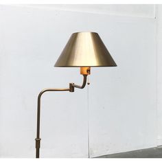 a lamp that is on top of a white wall next to a light fixture with a long arm