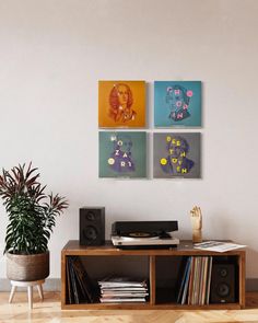 a living room with three paintings on the wall and a record player next to it