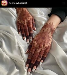 henna on the hands of a woman laying in bed with her hand painted brown and white