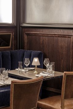 a dining room table set with place settings and wine glasses on the tables in front of it