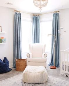 a baby's room with a white chair and blue drapes