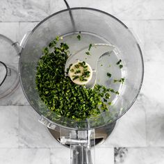 a food processor filled with chopped green vegetables