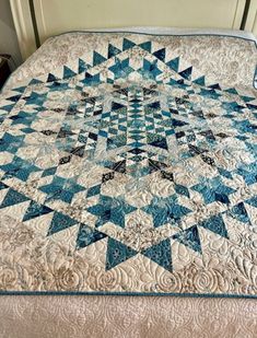 a blue and white quilt sitting on top of a bed