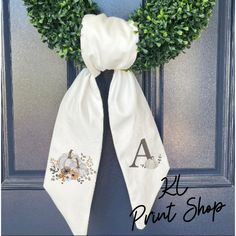 a door hanger with a wreath and monogrammed pumpkins on the front