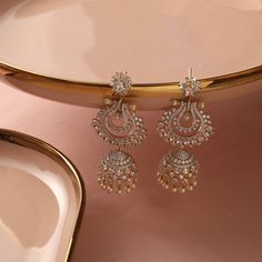 Description: Adorned with the best quality CZ stones, these dangling Jhumki earrings highlighted with pearl drops at the bottom elevate your festive ensemble. Featuring floral motifs, this is perfect for gifting your loved ones. Details & Specifications: Materials used: CZ stones with Gold Plating Weight -Earrings: 34.81 gm Length - Earrings: 7.5 cm Make it custom Want to make it a custom earring? Sure! Reach out to us at support@tarinika.com and we’ll be happy to make possible modifications at Elegant American Diamond Jhumkas For Festive Occasion, Diwali Reception Chandelier Earrings With Latkans, Festive Reception Jhumkas With Latkans, Diwali Reception Chandelier Drop Earrings, Diwali Reception Drop Chandelier Earrings, Diwali Reception Danglers With Latkans, Temple Jewelry Jhumkas With Pearl Drop For Reception, Temple Jewelry Pearl Drop Jhumkas For Reception, Dangle Jhumkas With Latkans For Reception