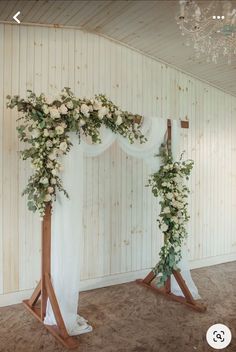 the wedding arch is decorated with white flowers and greenery for an elegant touch to the ceremony