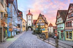 a cobblestone street lined with colorful buildings in germany at sunset or sunrise time