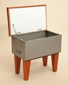 an old metal box sitting on top of a wooden stand with a mirror in it