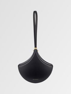 a black handbag hanging from the side on a white background with a gold handle