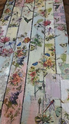 an old wooden table with flowers and butterflies painted on the top, along with other wood planks