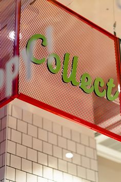 a red sign hanging from the side of a white tiled wall next to a brick wall