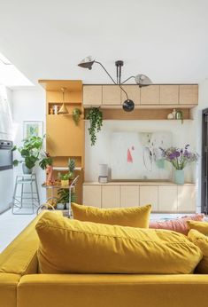 a living room filled with yellow furniture and lots of plants on the wall next to it