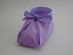 a purple vase with a bow on the top and bottom, sitting on a white surface