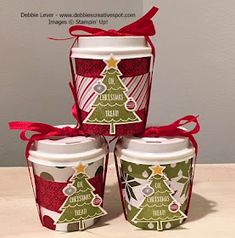 four coffee cups decorated with christmas trees and red bows are sitting on a table next to each other