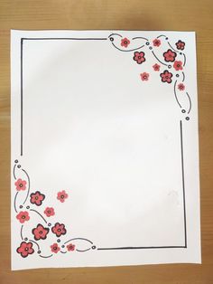 a piece of paper with red and black flowers on it, sitting on top of a wooden table