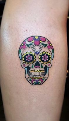 a woman's thigh with a colorful sugar skull tattoo on it