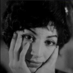 a black and white photo of a woman holding her hands to her face while looking at the camera