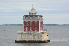 a red and white lighthouse sitting on top of a body of water