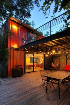 a deck with a table and chairs on it next to a red shipping container house