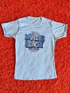 "1970s Myrtle Beach light blue tee with exposed stitching detail, so good! No tag - go by measurements below for best fit. Buyer is responsible for confirming fit and sales are final. Please reach out with any questions!  CONDITION: excellent vintage condition w/ no major wear MEASUREMENTS (taken laying flat then doubled where applicable:) 24\" long  33\" pit to pit - 38\" stretched 30\" waist  14\" shoulder Model is 5'2 34/27/38 for reference Follow us on Instagram for first dibs and special di Light Blue Crew Neck Beach T-shirt, Light Blue Crew Neck T-shirt For Beach, Light Wash Cotton Tops For Vacation, Light Blue Short Sleeve Tops For Beach Season, Retro Cotton T-shirt For The Beach, Retro Cotton T-shirt For Beach, Light Wash Summer Graphic Tee, Light Wash Cotton Beach Top, Vintage Cotton Beach Tops