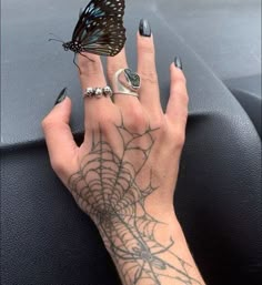 a woman's hand with tattoos and a butterfly on her wrist, next to a car steering wheel