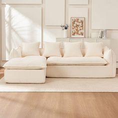 a white couch sitting on top of a hard wood floor next to a wall with pictures