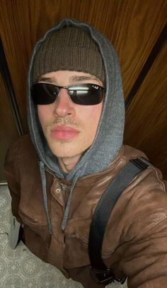 a man wearing sunglasses and a hoodie is taking a selfie