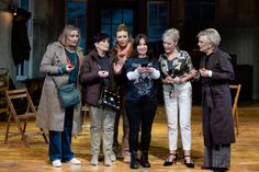 five women standing together on a stage with one holding a baby in her arms and the other clapping