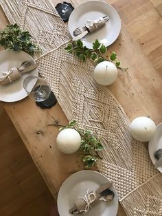 a wooden table topped with white plates and silverware