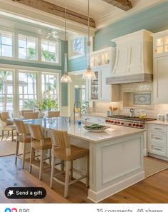 a kitchen with white cabinets and an island in the middle, surrounded by windows that look out onto the ocean