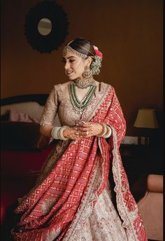 a woman in a red and white bridal outfit is standing with her hands on her hips