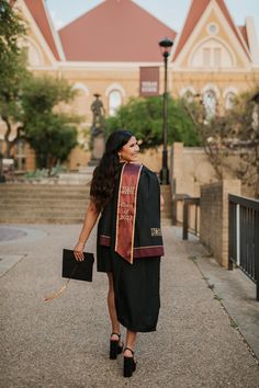 a woman walking down the street in front of a building wearing a graduation gown and carrying a briefcase