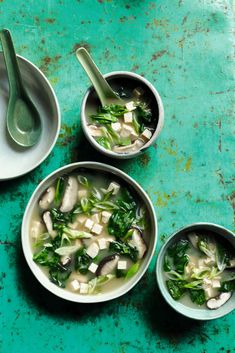 three bowls filled with soup on top of a green table