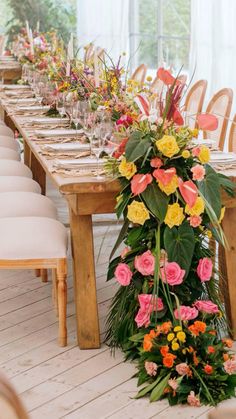 a long table with flowers and greenery is set up for an outdoor dinner party