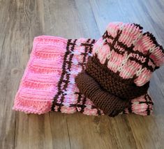 three knitted items are laying on the floor next to each other, one pink and one brown