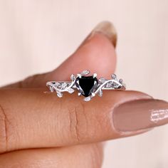 a woman's hand holding an engagement ring with a heart shaped black diamond in the middle