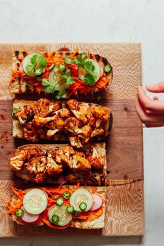 a person is holding a wooden cutting board with different types of food items on it