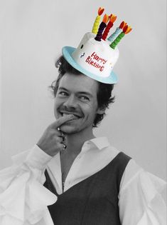 a man wearing a birthday hat with candles on it's top and holding his finger to his mouth