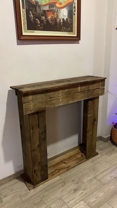 a wooden table sitting in the corner of a room with a painting on the wall