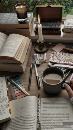 an open book on a table next to a cup of coffee and some books with candles