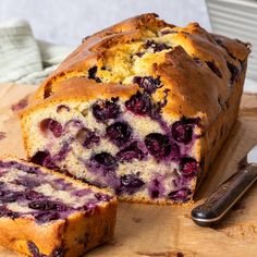 a loaf of blueberry bread sitting on top of a wooden cutting board