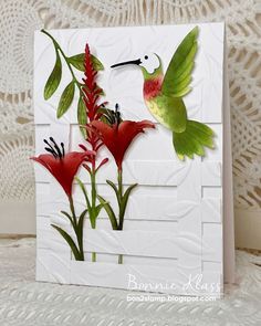 a close up of a card with flowers and a hummingbird on it's side