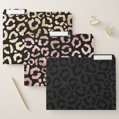 four different leopard print envelopes on a table with pen and notepad next to them