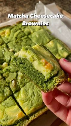 a hand holding a piece of matcha cheesecake brownies