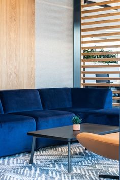 a blue couch sitting in front of a wooden wall next to a table and chair