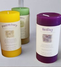 three different colored candles sitting next to each other on a white surface with the words positive energy written on them