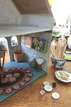 a doll house is sitting on top of a table with plates and bowls around it